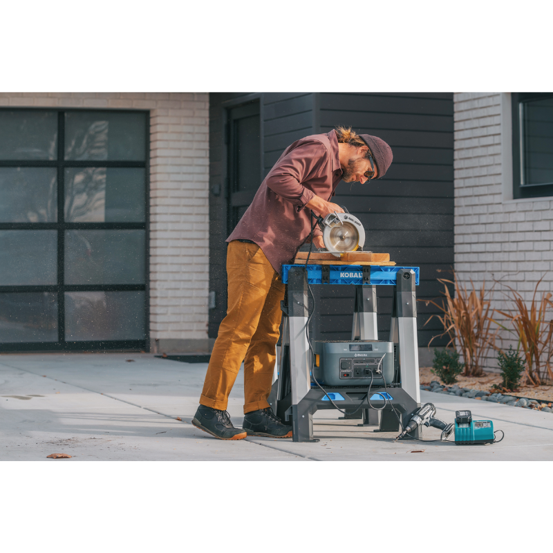 A man using an electric saw plugged in a BaseCharge 1500.