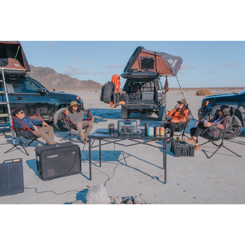 Group of people camping on a desert using BaseCharge 600 to charge their equipments. 