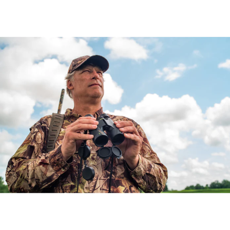 A man wearing a hunting gear and outfit holding a Alpen Apex 8x42 Binoculars.