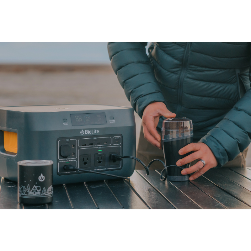 A person out in the desert  using a BaseCharge 1500 to grind coffee. with 