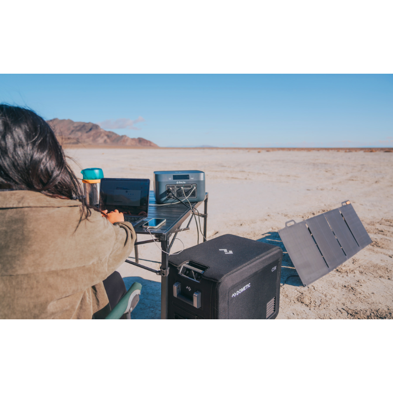 A woman charging BaseCharge 1500 with solar panels in the desert. 